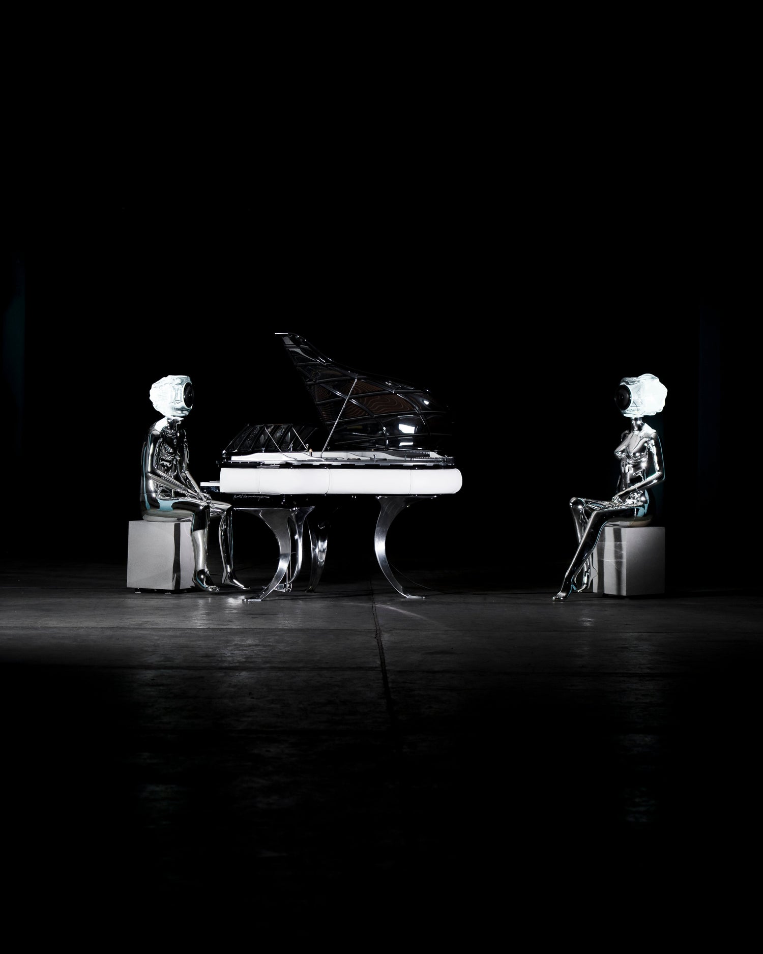 Audiomus is a audio design a chrome metallic sculpture of a seated figure on a concrete base with build in subwoofer and a mouth-blown glass sphere with light and the speaker driver built in 
